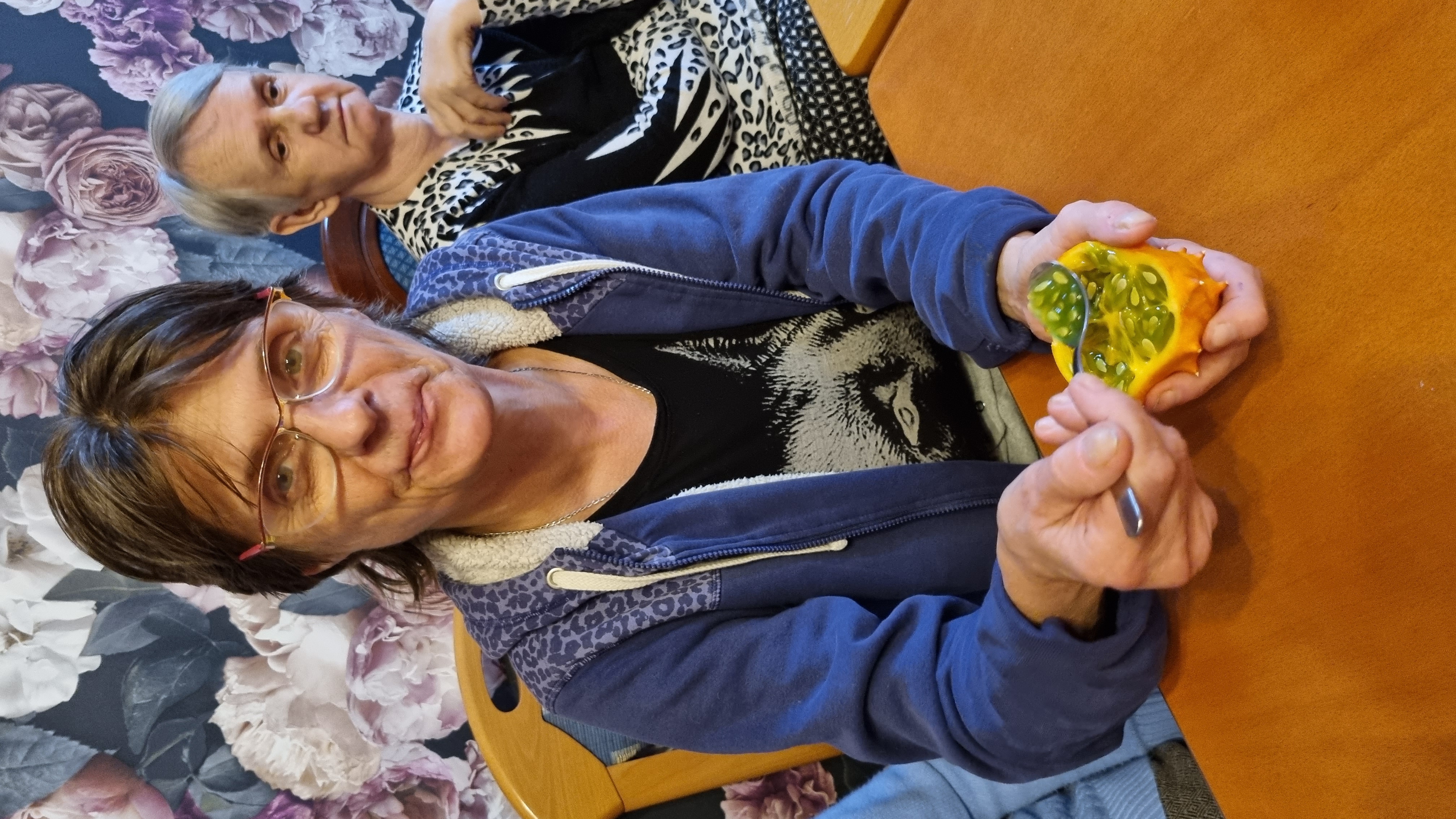 Seniorka prezentuje do zdjęcia przecięty na pół egzotyczny owoc