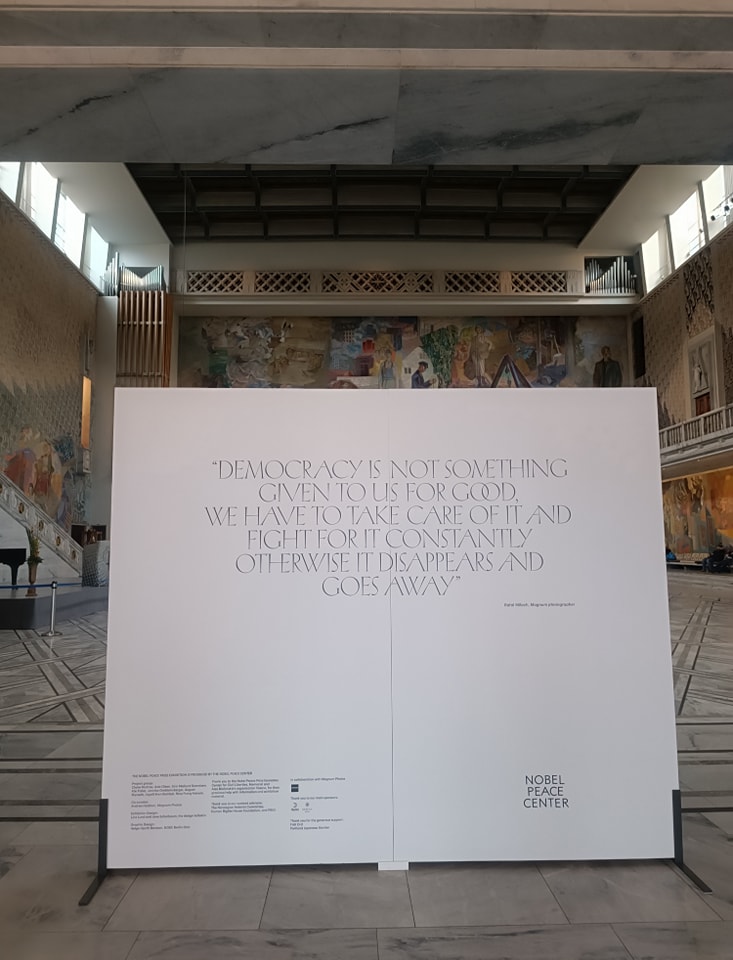 Biała tablica na której jest napisane "Democracy is not something given to us for good. We have to take care of it and fight for it constantly otherwise it disappear and goes away." Nobel peace center. Tablica znajduje się się w budynku ratusza w Oslo.