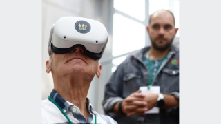 Senior zanurza się w wirtualnej rzeczywistości. Na głowie ma gogle VR. W tle jeden z trenerów CREO - Dawid.