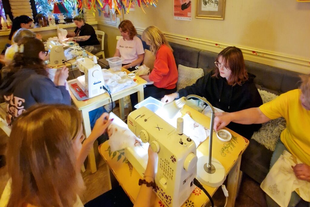 Na zdjęciu widać grupę kobiet, które w restauracji Umberto szyją torby dla kobiet chorujących na raka