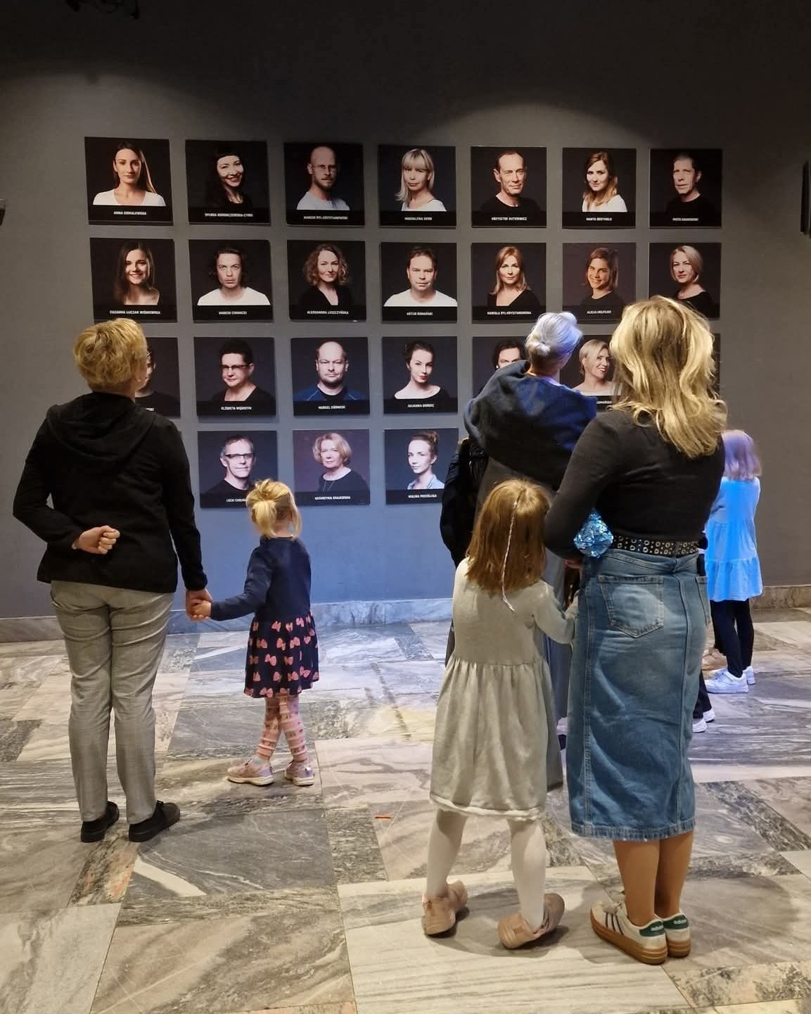 Zdjęcie przedstawia ludzi oglądających wystawę zdjęć